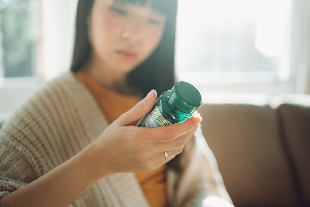 Out of focus woman looking at natural supplement bottle