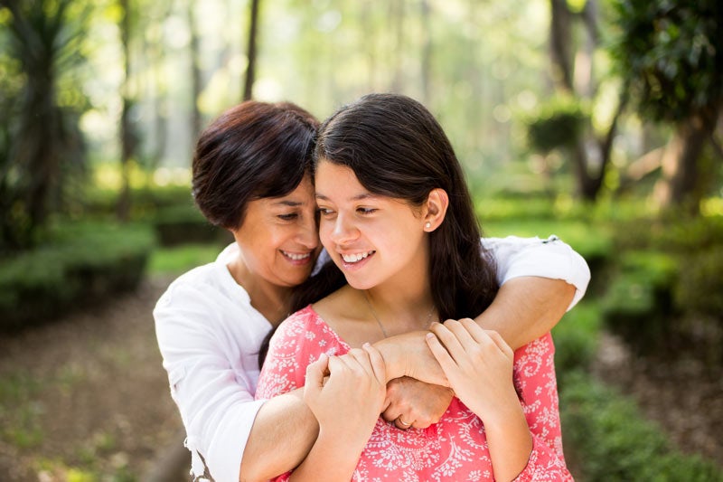 Mother hugging teen daughter