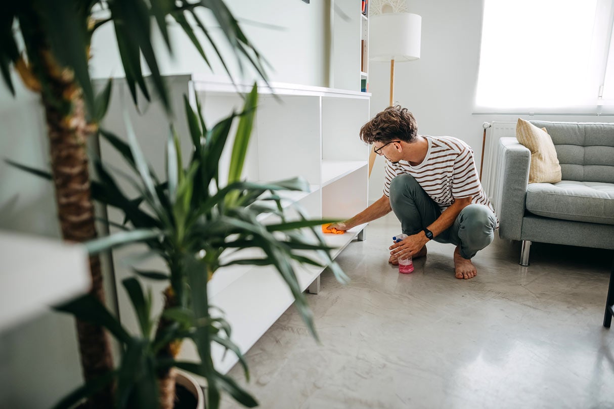 Man dusting shelves in home