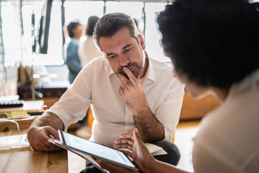 Mature man looking at a digital tablet with a colleague