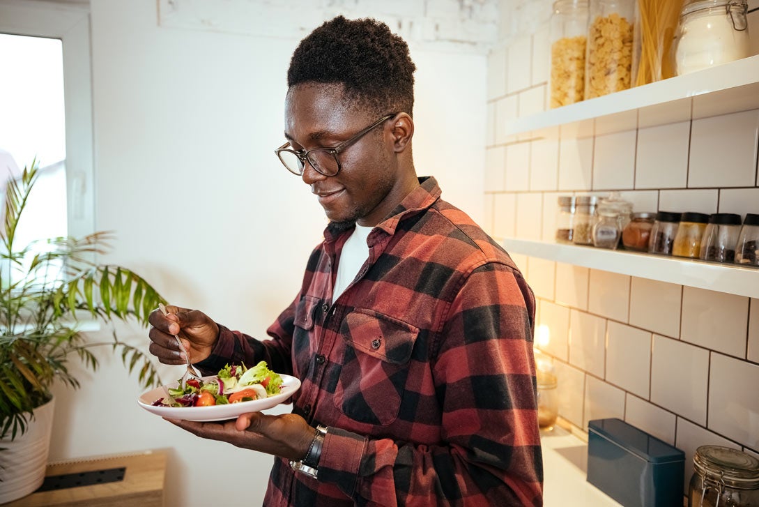 Man eating a healthy salad at home in kitchen