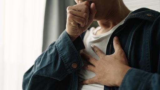 Young man coughing and holding chest