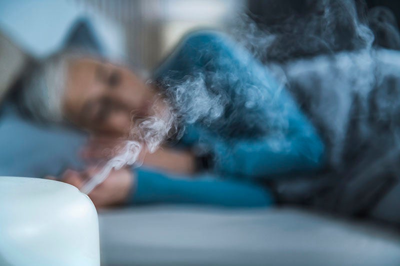 Woman sleeping with a humidifier next to bed