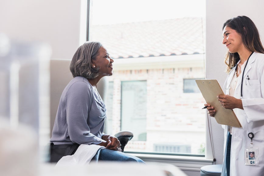 Mature woman talking to doctor in exam room
