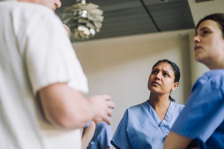 Two nurses speaking with man in white clothes