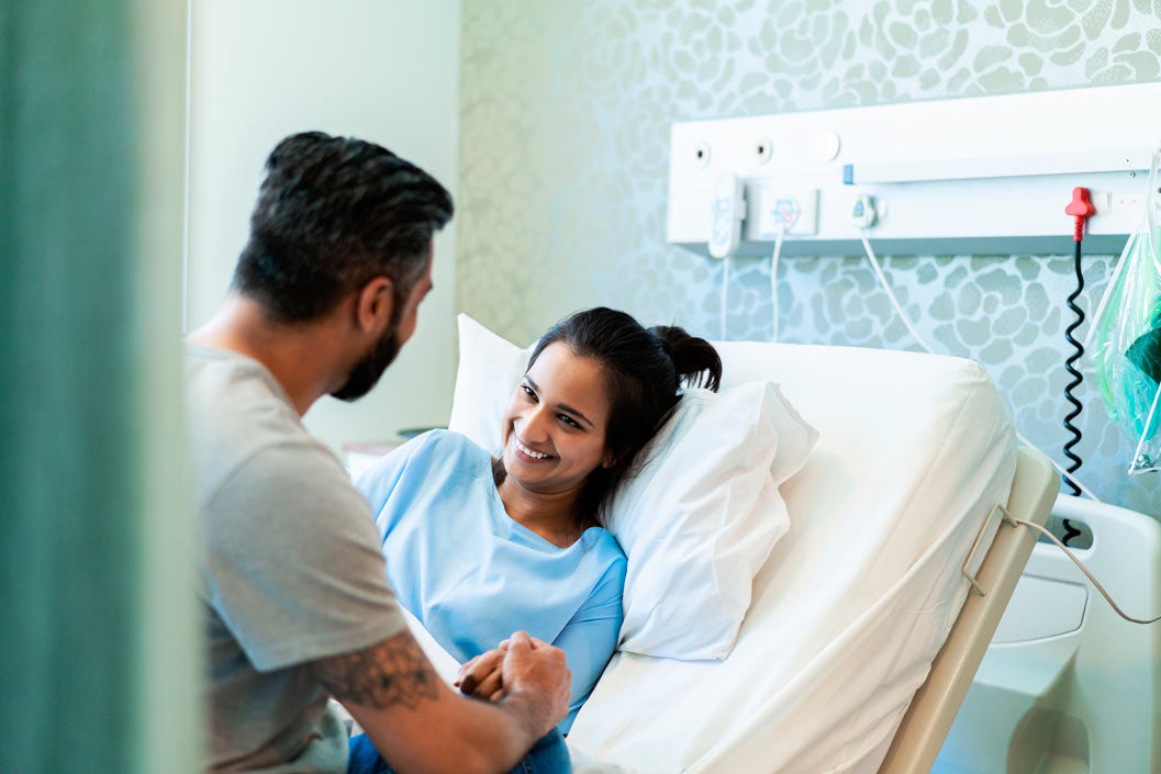 Smiling female patient looking at man in hospital